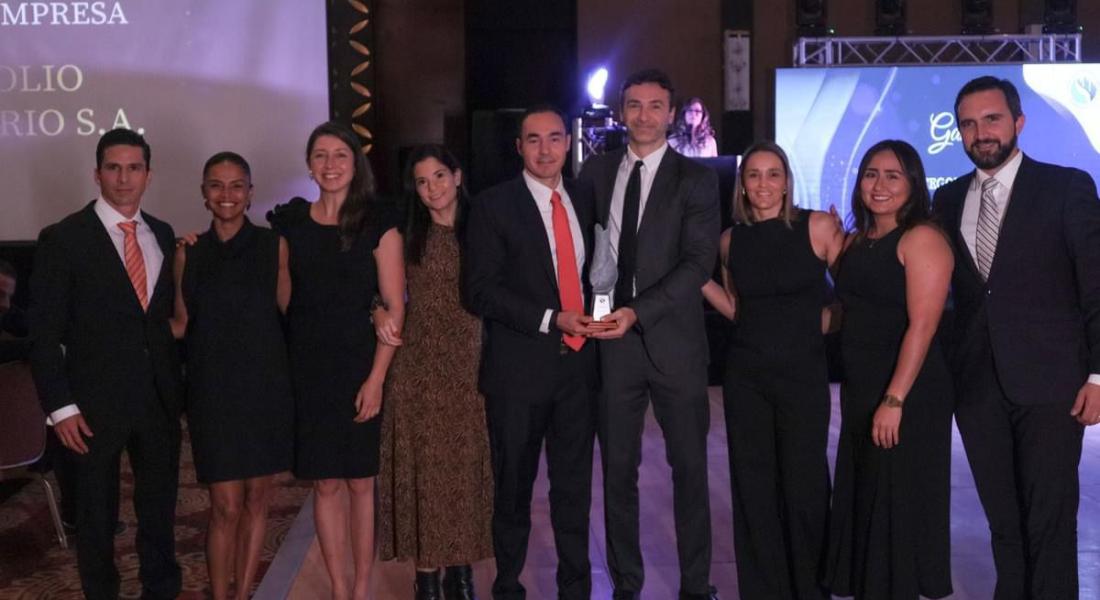 Equipo de Portafolio Inmobiliario posando en una ceremonia de premiación, donde reciben un reconocimiento. Los miembros del equipo están vestidos de manera formal y se muestran sonrientes y unidos, sosteniendo el trofeo que simboliza su logro