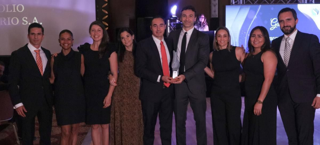 Equipo de Portafolio Inmobiliario posando en una ceremonia de premiación, donde reciben un reconocimiento. Los miembros del equipo están vestidos de manera formal y se muestran sonrientes y unidos, sosteniendo el trofeo que simboliza su logro